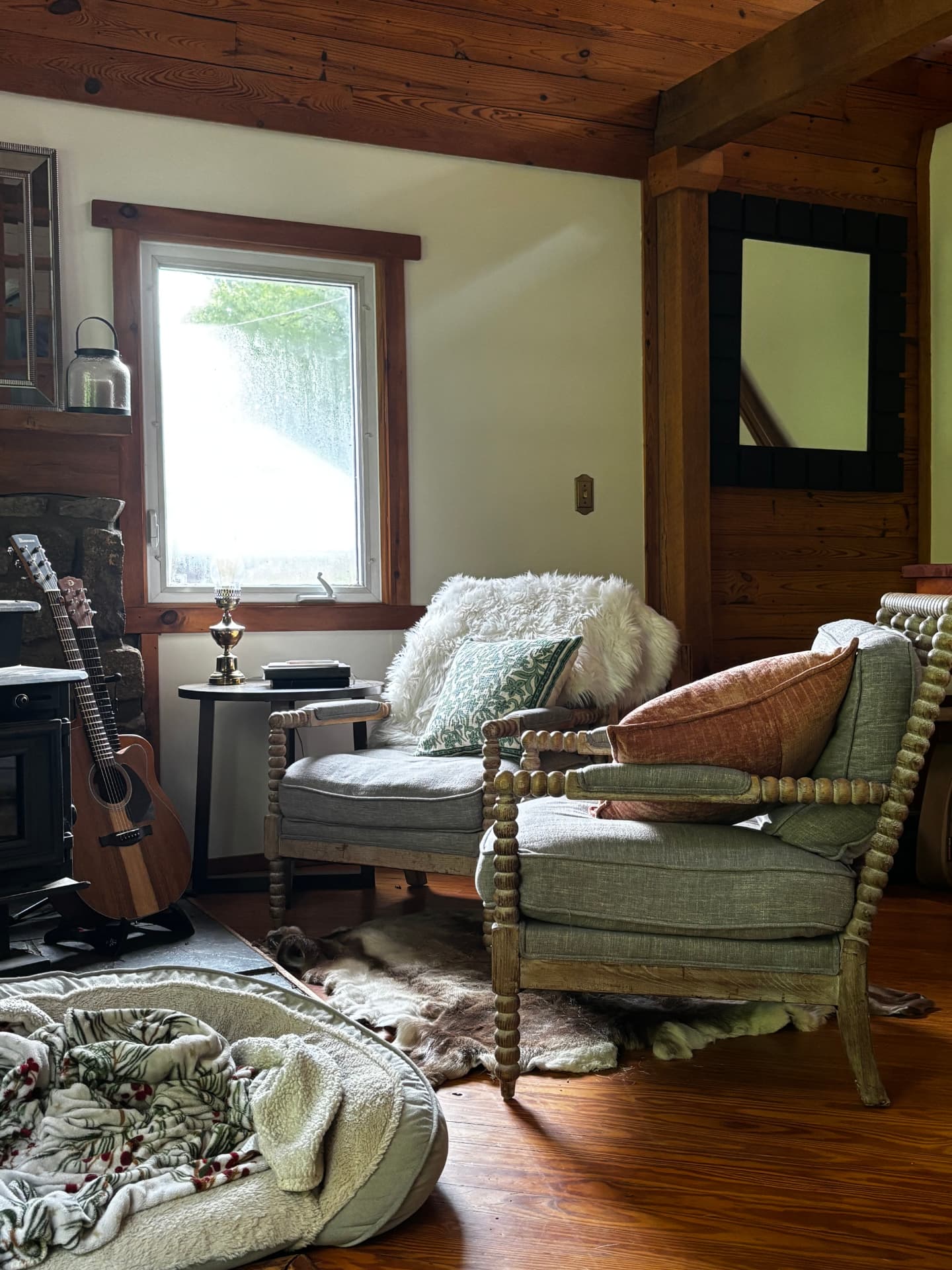 Two grey armchairs beside a window in a wood-paneled room at Free Holler Farm